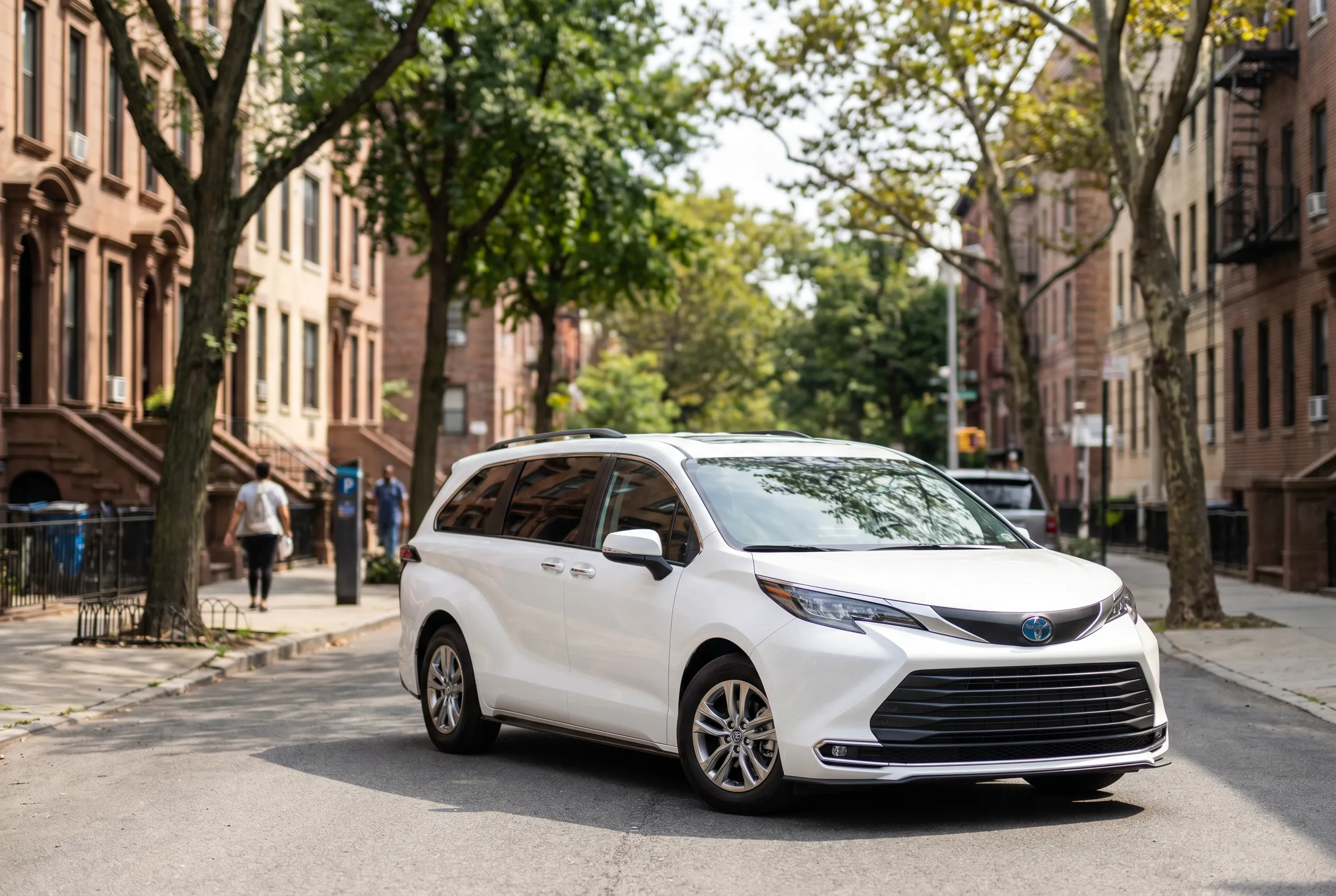 A white Toyota Sienna parked on a tree-lined Bronx street